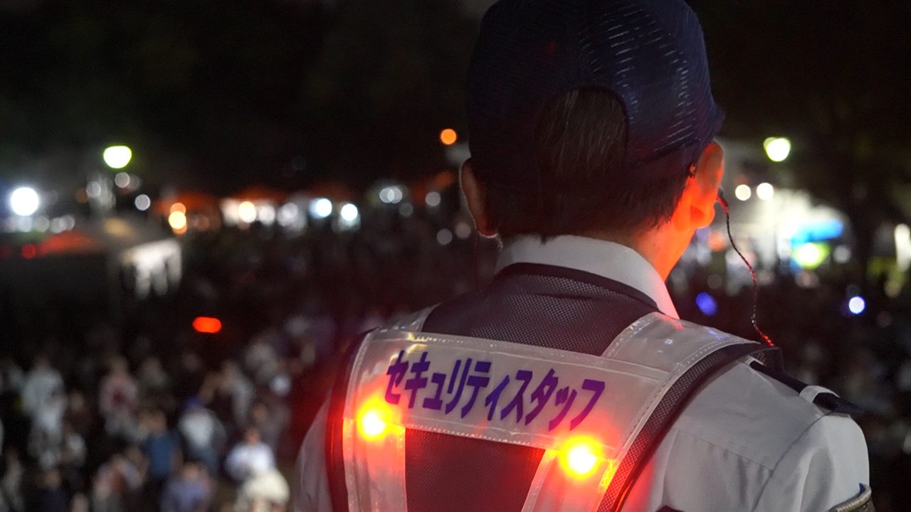 夜のイベント会場で雑踏警備にあたる警備員