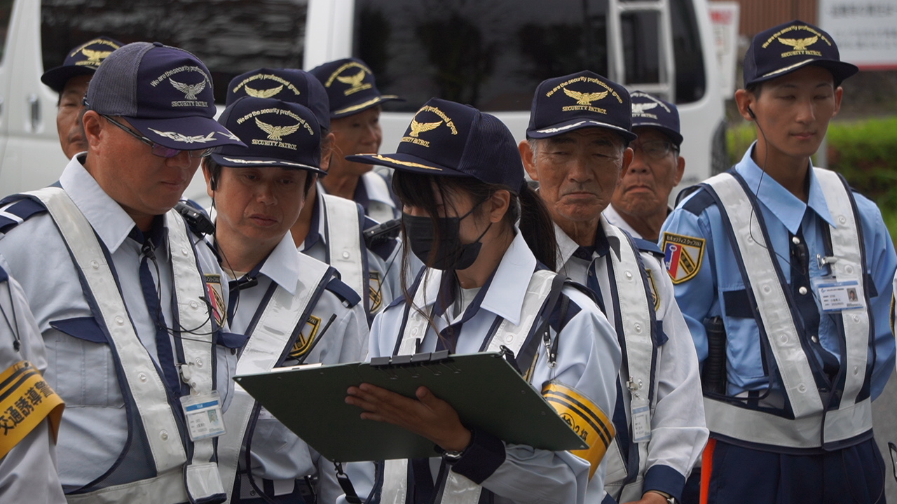 先輩警備員から研修を受ける50代の新人警備員