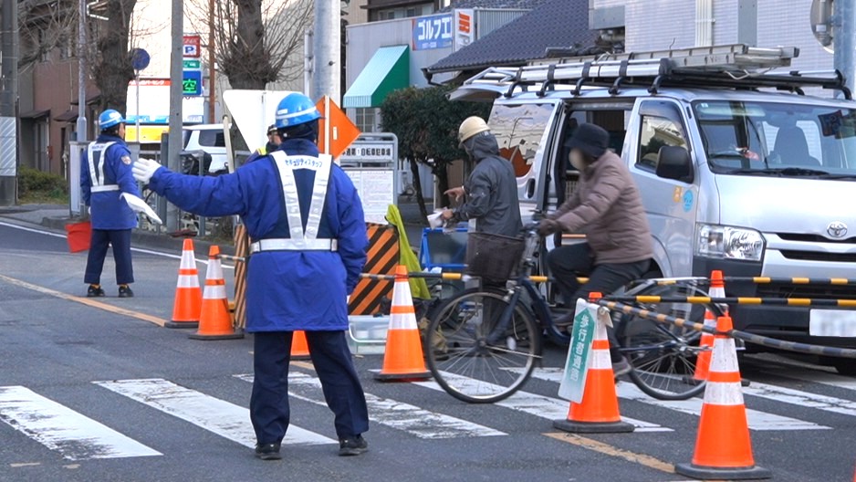道路で車と人を案内する交通誘導警備員